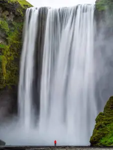 Island Fotoreisen - skogafoss, Frau mit roter Jacke, riesiger Wasserfall