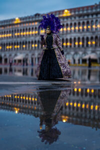 Karnevalsmaske Venedig zur blauen Stunde – Kostümierte Person mit Wasserspiegelung auf dem Markusplatz, Fotoreise Karneval Venedig.